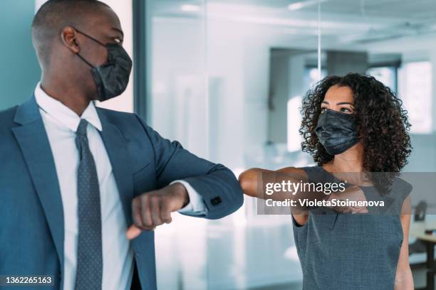 gente de negocios saludando durante la pandemia de covid-19 - elbow bump fotografías e imágenes de stock