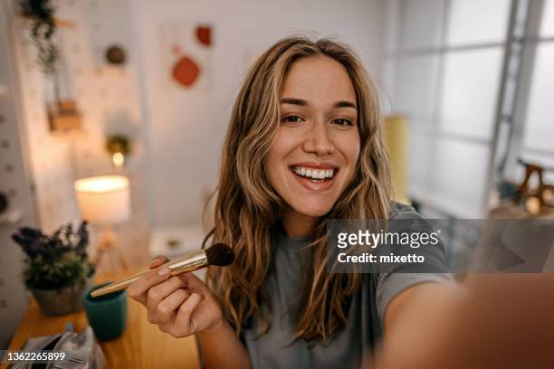 woman applying make-up with brush and recording vlog - selfie woman stock pictures, royalty-free photos & images