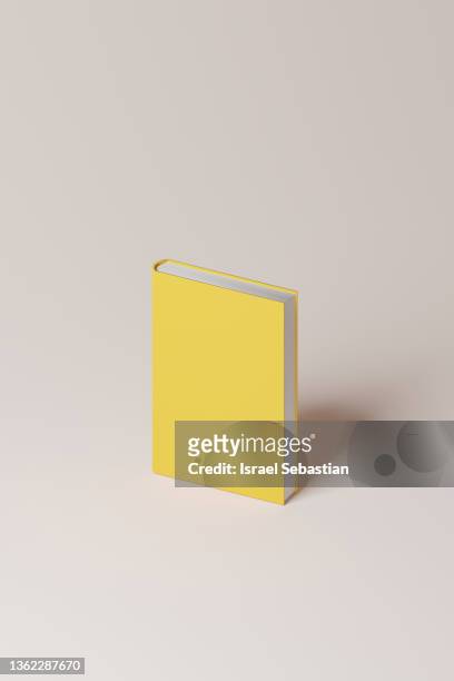 digitally created image of a yellow hardcover book on a pink background with copy space. - novel photos et images de collection