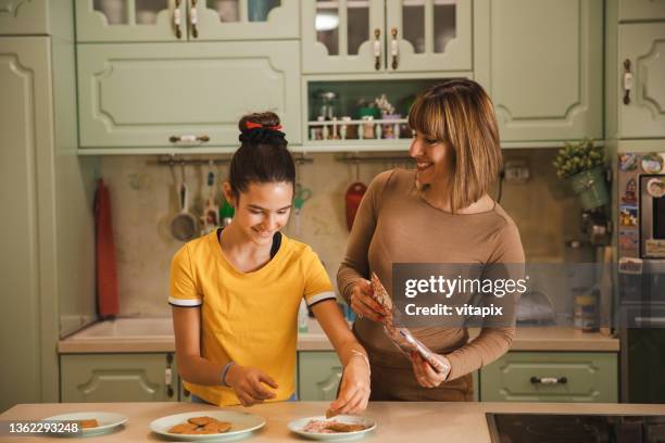 mother and her preteen daughter in the kitchen - teenagers eating with mum stock pictures, royalty-free photos & images