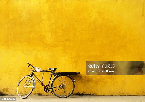 Old Bicycle parked against worn yellow wall