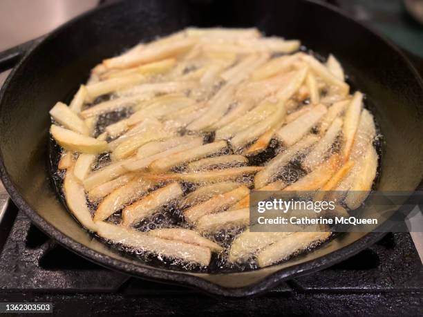 pan frying batch of homemade fresh cut french fries in cast iron pan - batata frita imagens e fotografias de stock