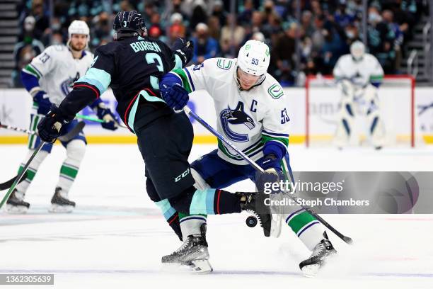 Will Borgen of the Seattle Kraken and Bo Horvat of the Vancouver Canucks battle for a loose puck during the first period at Climate Pledge Arena on...