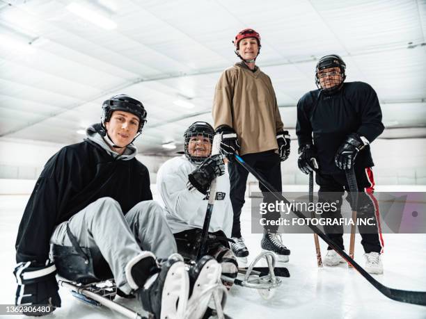 reife behinderte lateinerin mit ihrer familie und freunden, die sledgehockey übt - team canada hockey stock-fotos und bilder