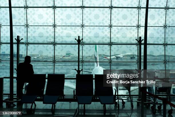 Passenger looks through a window at Dubai International Airport on January 01, 2022 in Dubai, UAE. Inter-country journeys made during the Omicron...