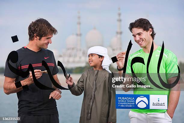 Roger Federer of Switzerland and Rafael Nadal of Spain take part in a unique Arabic calligraphy session with a young United Arab Emirates national as...