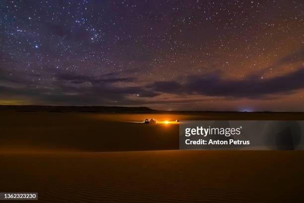 camp in the desert with a bonfire under the starry sky. - bonfire stock pictures, royalty-free photos & images