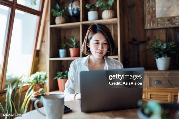 junge asiatin, die von zu hause aus arbeitet, videokonferenzen mit geschäftspartnern auf laptop-computer im heimbüro. remote-arbeit, freelancer, kleinunternehmer-konzept - direct stock-fotos und bilder