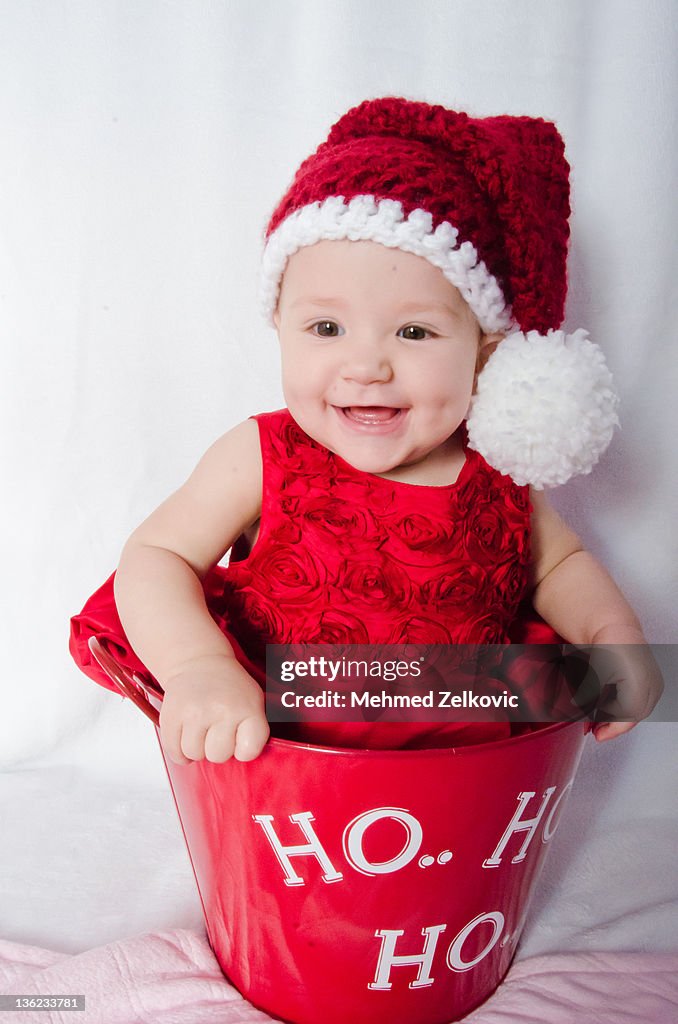 Christmas baby portrait in bucket wearing Santa ha