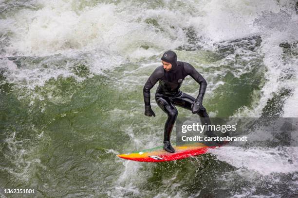 young man surfing on a river in the center of munich - eisbach river stock pictures, royalty-free photos & images