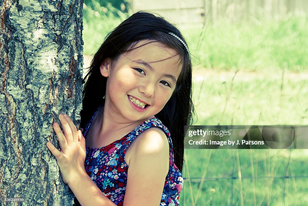 Girl giving pose beside tree
