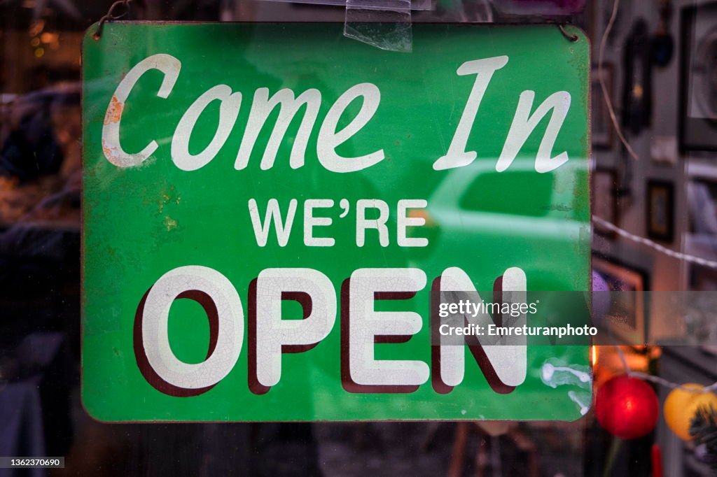 "Open" sign hanging on a store window.