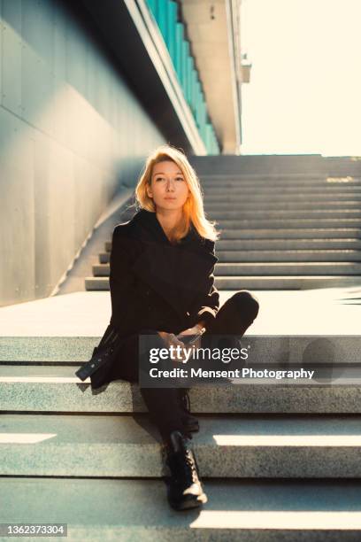 confident business woman with mobile technology in sitting on a staircase in the middle of town - man stairs sitting stock-fotos und bilder