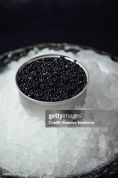 black caviar in a silver jar on ice on a dark background - 魚卵 ストックフォトと画像