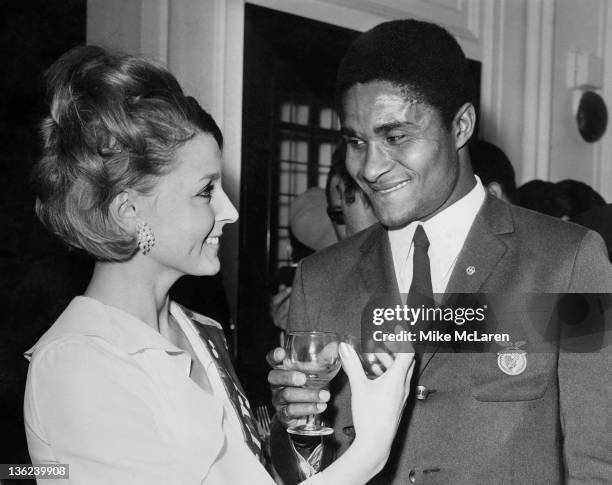 Portuguese footballer Eusebio at a reception for his team, Benfica, at the Burberry store in Haymarket, London 30th May 1968. With him is 'Miss...