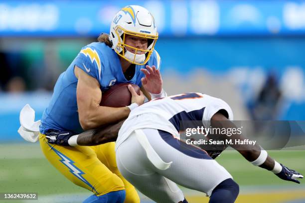 Justin Herbert of the Los Angeles Chargers is tackled on a run by Nate Hairston of the Denver Broncos during the second quarter of the game at SoFi...