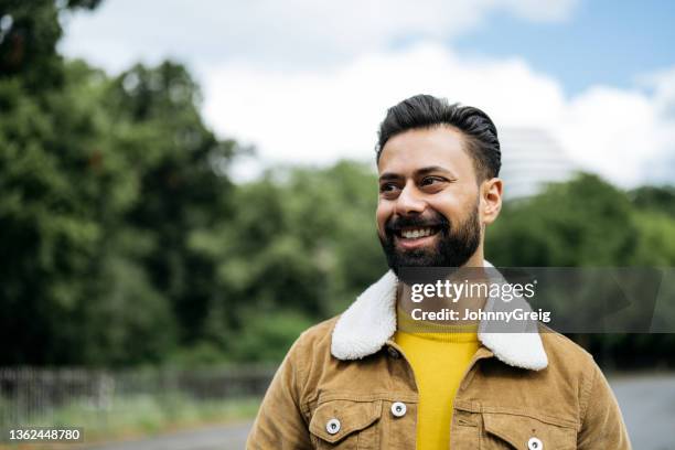 candid portrait of early 30s indian man standing outdoors - beige coat stockfoto's en -beelden