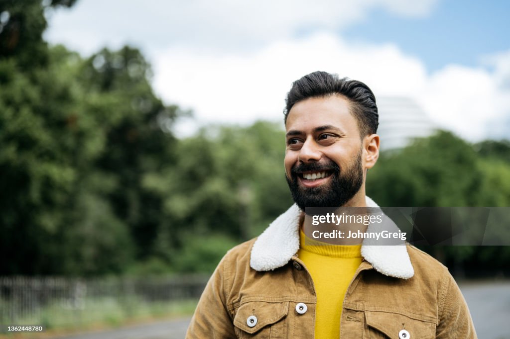 Candid portrait of early 30s Indian man standing outdoors