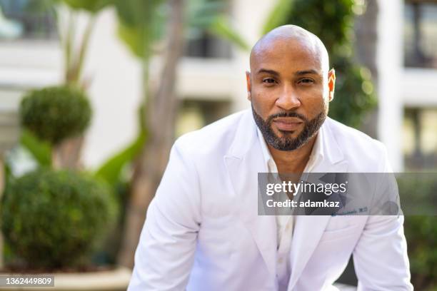 attractive black doctor smiling outdoors - testimonial stockfoto's en -beelden