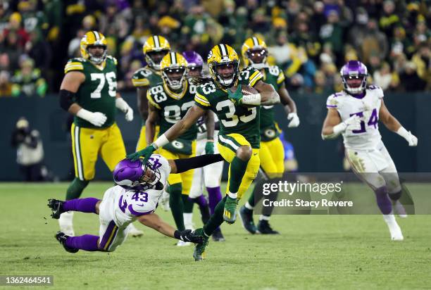 Running back Aaron Jones of the Green Bay Packers carries the ball as he avoids a tackle by safety Camryn Bynum of the Minnesota Vikings during the...