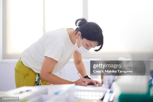 woman working in an office during the covid-19 pandemic - working mother ストックフォトと画像