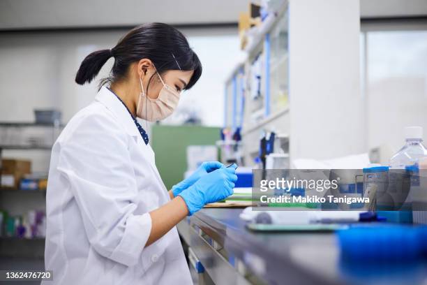 woman researching and developing health care products - biotechnologie stockfoto's en -beelden