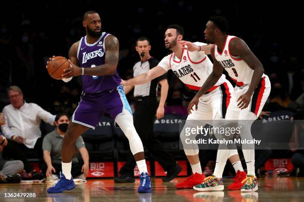 LeBron James of the Los Angeles Lakers looks to pass the ball against Larry Nance Jr. #11 and Nassir Little of the Portland Trail Blazers during the...