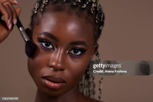 portrait of beautiful afro woman with make-up holding  make-up brush - alena model stockfoto's en -beelden