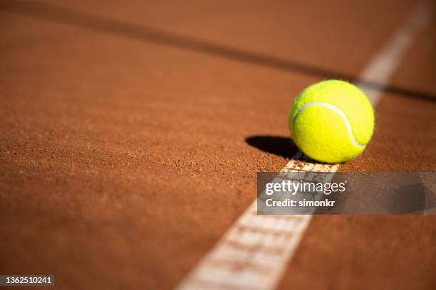 tennis ball on clay court. - tennisser stockfoto's en -beelden