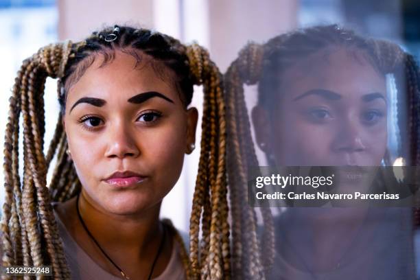 portrait of a latina young woman with braided hair next to a window - face symmetry stock pictures, royalty-free photos & images