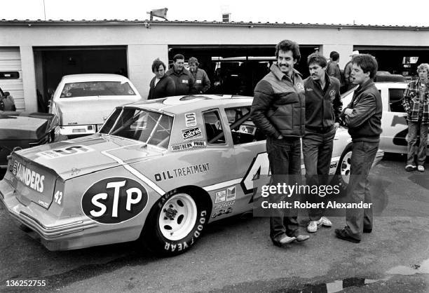 Driver Kyle Petty, left, talks with members of his racing crew while waiting their turn to push the car into the NASCAR Inspection Station in the...