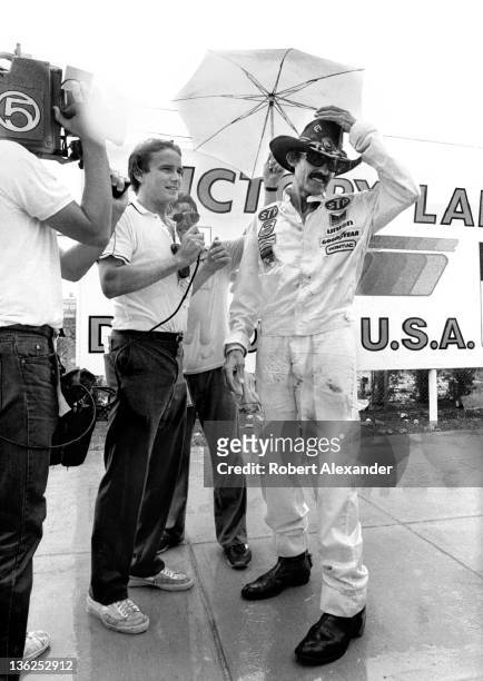 As rain begins to fall, Richard Petty, driver of the STP Pontiac, talks with a TV reporter in Victory Lane at the Daytona International Speedway on...
