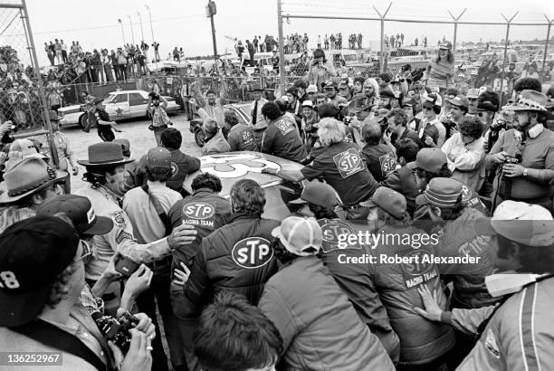 Members of NASCAR driver Richard Petty's racing team push Petty's STP Pontiac toward Victory Lane at the Daytona International Speedway on July 4,...