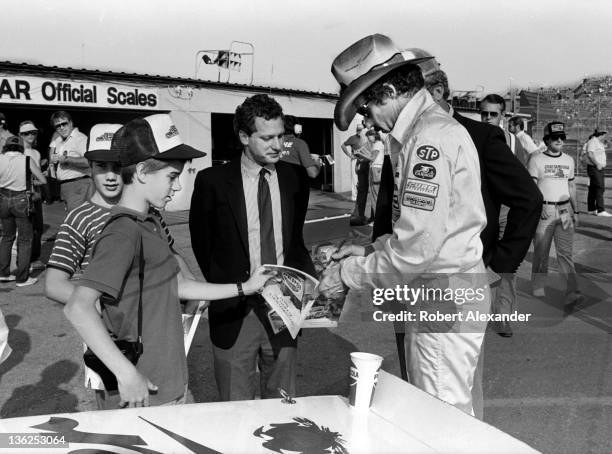 Richard Petty, driver of the STP Pontiac, signs an autograph in the Daytona International Speedway infield prior to the running of the 1985...