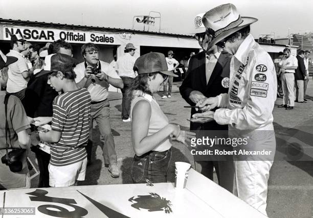 Richard Petty, driver of the STP Pontiac, signs an autograph in the Daytona International Speedway infield prior to the running of the 1985...