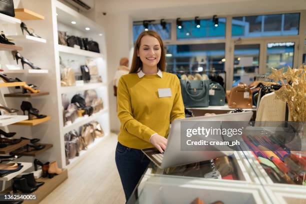 gérant d’un magasin de vêtements et de chaussures utilisant un ordinateur portable - magasin de chaussures photos et images de collection