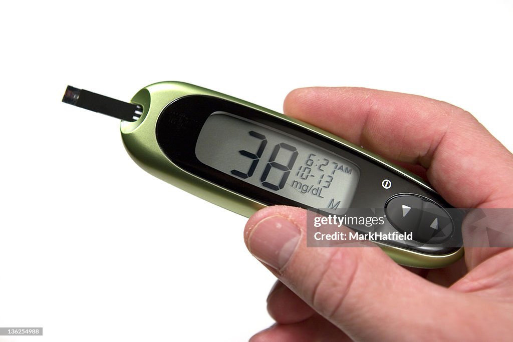 Glucose monitor displaying 38mg/dL being held by a person