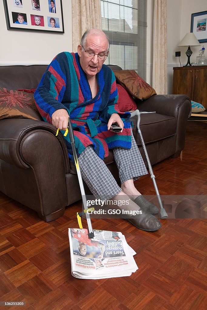 Senior male uses grab aid to pick up newspaper