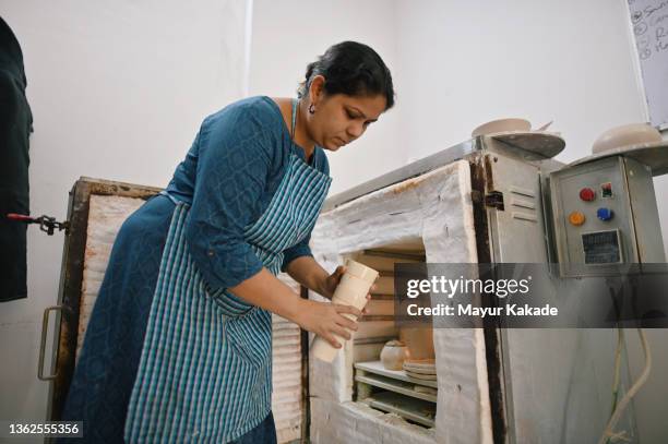 woman ceramic artist keeping her ceramic plates and bowls in kiln - kiln stock pictures, royalty-free photos & images
