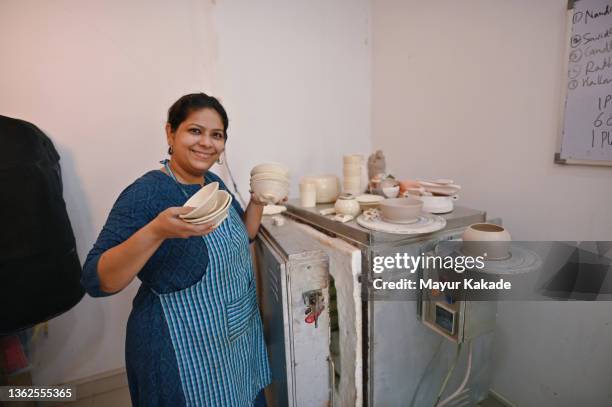 woman ceramic artist showing her ceramic crockery after taking out from kiln - pottery kiln stock pictures, royalty-free photos & images