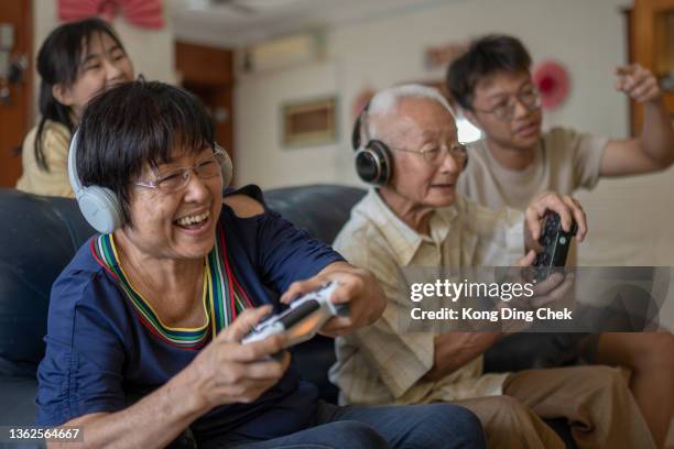 2 asian chinese grandparent playing video game at home with grandchildren. - game 2 2 stock pictures, royalty-free photos & images
