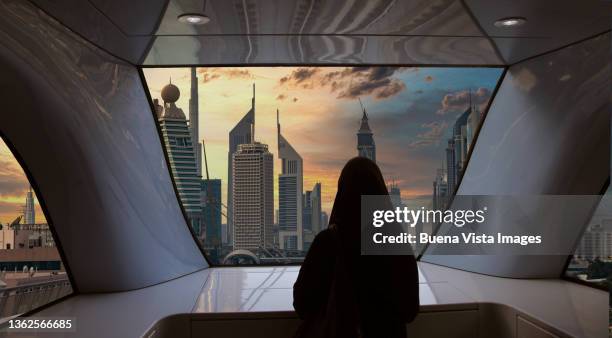 woman with abaya watching futuristic city - dubai metro stock pictures, royalty-free photos & images