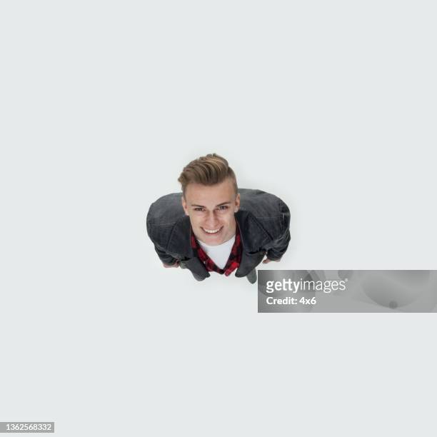 caucasian young male standing in front of white background wearing leather jacket - person look up from above stock pictures, royalty-free photos & images