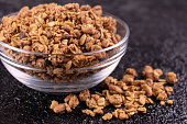 Healthy homemade muesli in a glass bowl on a black background. Close-up.