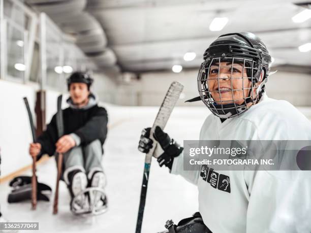 mature disabled latin woman and her friend practising sledge hockey - female hockey player stock pictures, royalty-free photos & images