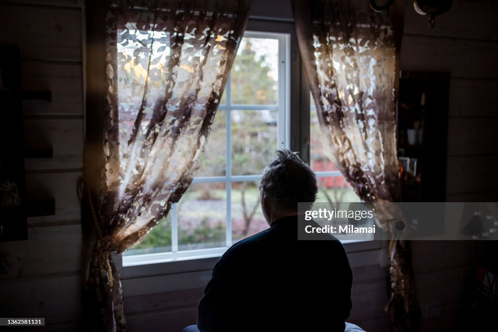 Lonely senior man looking out of window
