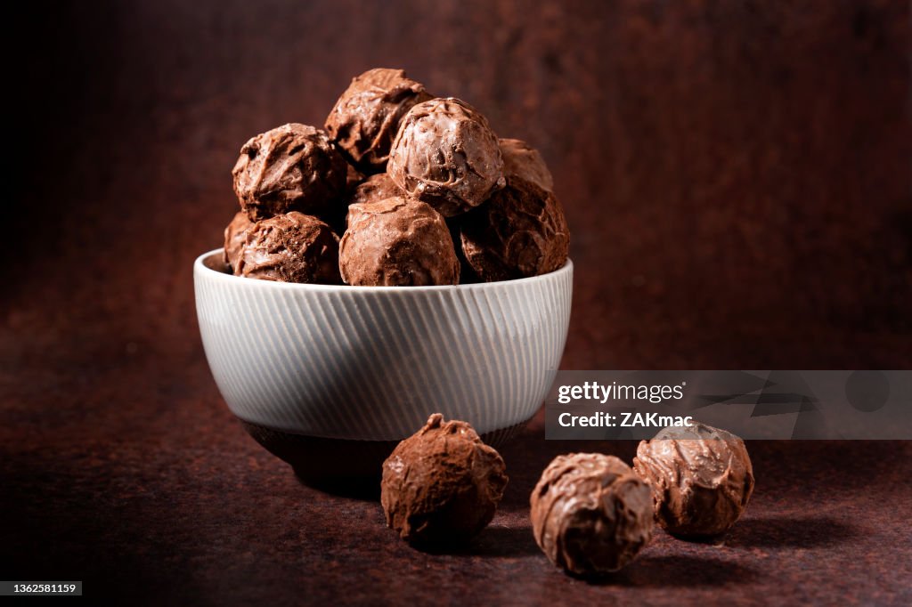 Schokoladentrüffel in einer Schüssel, fotografiert auf einem braunen Hintergrundfoto