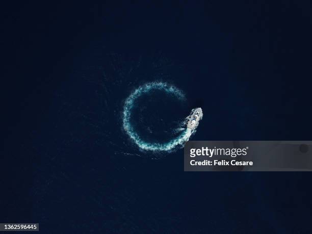 aerial view of a motorboat circling in deep blue ocean. - kielwasser stock-fotos und bilder
