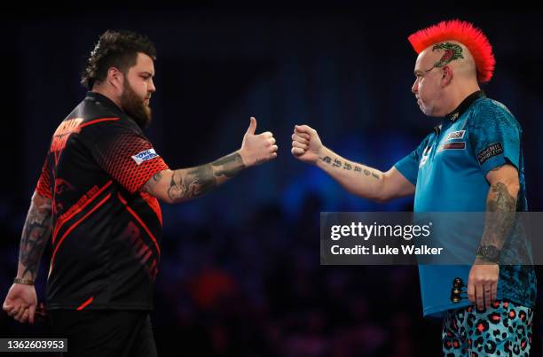 Michael Smith of England and Peter Wright of Scotland fist pump during the Finals on Day Sixteen of The William Hill World Darts Championship at...