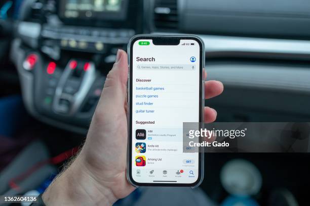 Person's hand holding the Apple iPhone 13 Pro in an automobile, Lafayette, California, with screen showing the App Store, December 29, 2021. Photo...